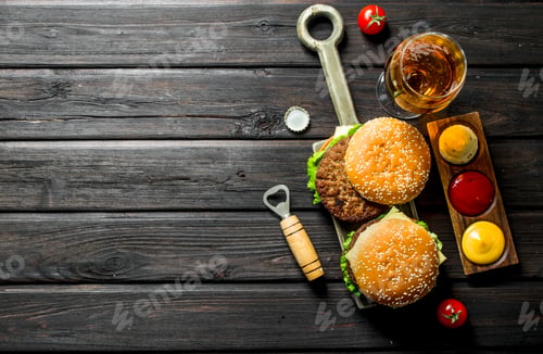 Preview: Burgers with beer in a glass and different sauces.