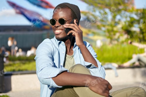 Preview: Positive young male with dark skin, smiling broadly while having conversation with his best friend,