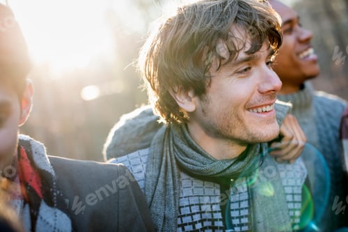 Preview: Two smiling men standing in a sunlit forest in autumn.