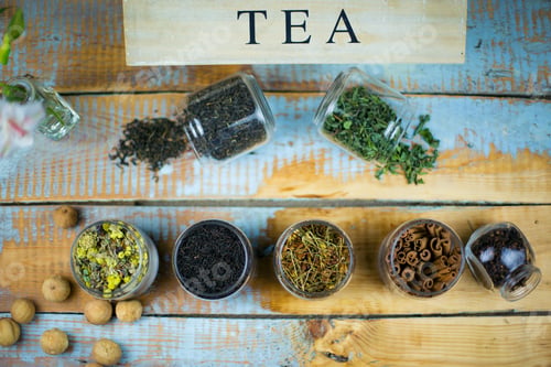 Preview: High angle shot of herbal tea leaves and cinnamon in jars on the table