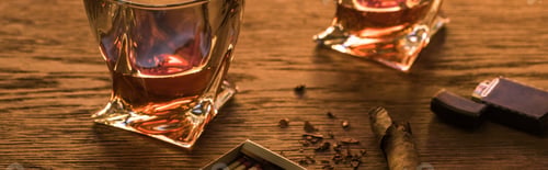 Preview: Glasses of brandy with cigar, lighter and matches on wooden table, panoramic shot
