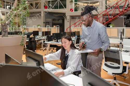 Preview: two multiracial coworkers sitting at a table in a coworking space working together