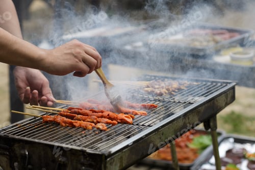 Preview: Man’s hands cooking barbecue on backyard at hot summer day