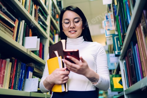 Preview: Young woman browsing smartphone in library