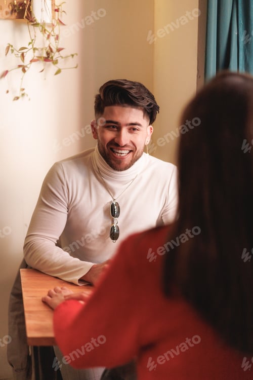 Preview: Excited latin man talking with his female friend in a coffee shop. Selective focus.