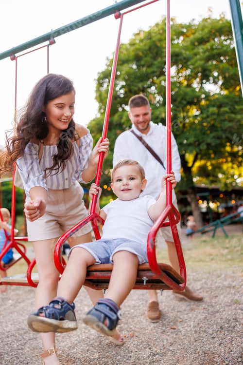 Preview: Mother and father playing with child on the playground