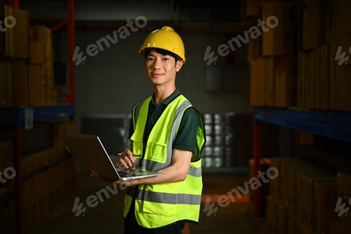 Preview: Female warehouse workers wearing hardhat holding laptop