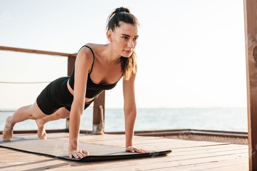 Preview: Fitness woman outdoors at the beach making plank exercise