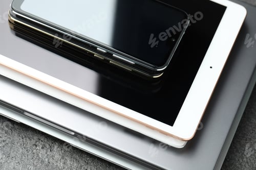Preview: Stack of electronic devices on grey table, closeup