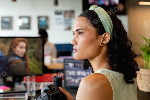 Preview: Biracial young businesswoman with camera at desk in office