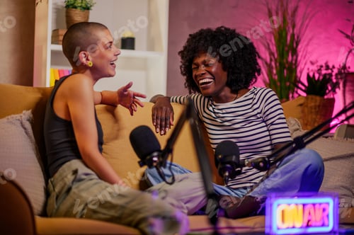 Preview: Two multiracial women recording episode of internet podcast in a modern studio