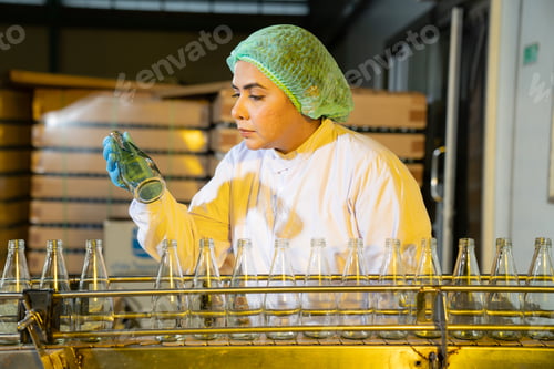 Preview: Woman worker quality control a fruit drink factory in glass.