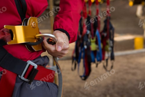 Preview: Hiker man adjusting his harness in the forest on a sunny day