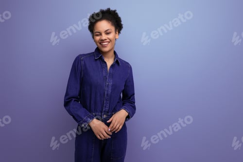 Preview: young brunette latin woman in blue denim overalls on background with copy space