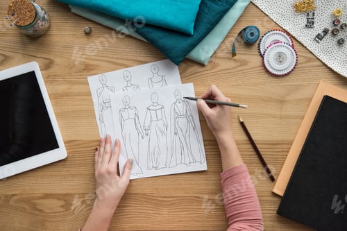 Preview: top view of cropped female hands drawing draft at seamstress workplace
