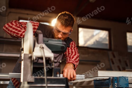 Preview: Young man work in home workshop garage with a grinder cuts metal bar