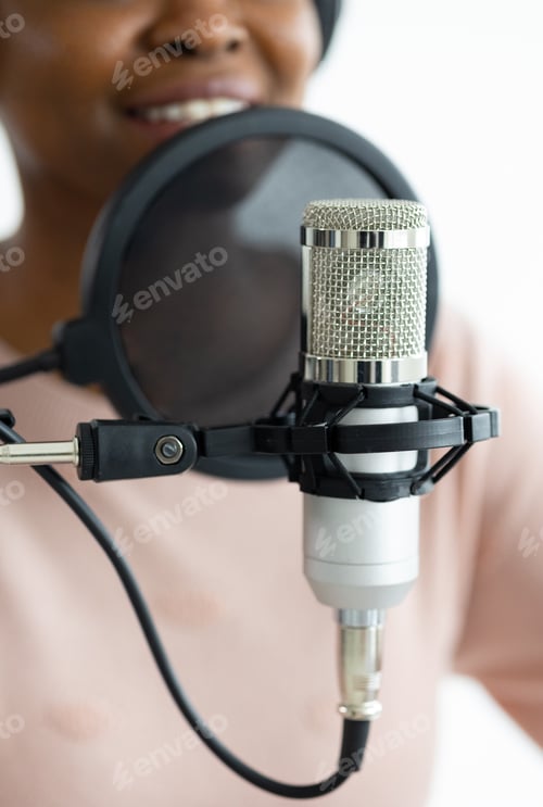 Preview: microphone close-up, young and beautiful African American woman in a recording studio recording