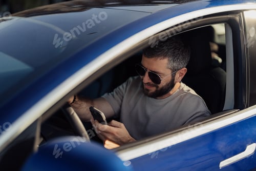Preview: Man using smartphone in electric car on sunny day