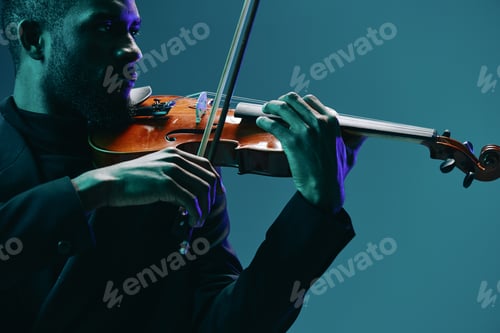 Preview: Classical musician in elegant attire performing on violin under a soft blue spotlight on stage with