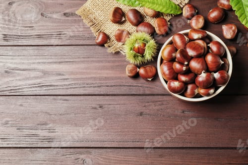 Preview: Fresh sweet edible chestnuts on brown wooden table, flat lay. Space for text