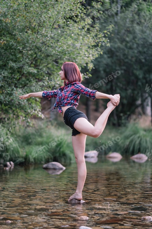 Preview: Pretty red haired girl performs exercises by the river.