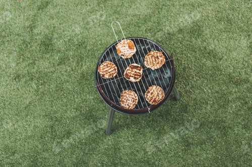 Preview: top view of grill with hamburgers standing on green grass