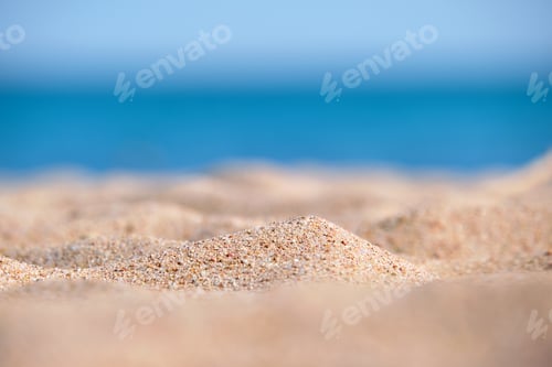 Preview: Close up of clean yellow sand surface covering seaside beach with blue sea water on background