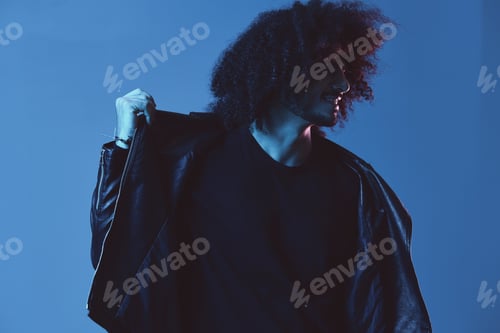 Preview: Portrait of fashion man with curly hair on blue background multinational, colored light, black