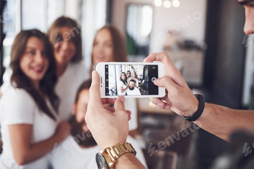 Preview: Blur portrait of blissful young best friends with hands holding phone on foreground