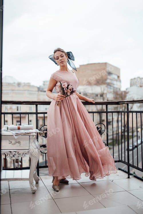 Preview: Millennial candid authentic lady in grace finery dress with bouquet of tulips at Paris balcony
