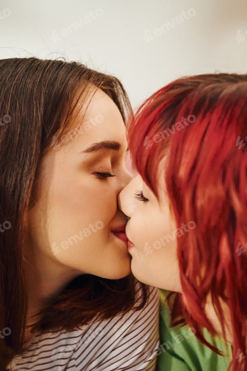 Preview: portrait of happy lesbian women kissing while having cozy and sweet moment in bedroom, lgbtq