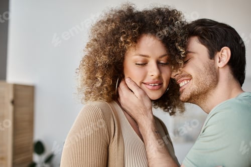 Preview: Couple in love of handsome man and curly woman at home in the morning, smiling and hugging