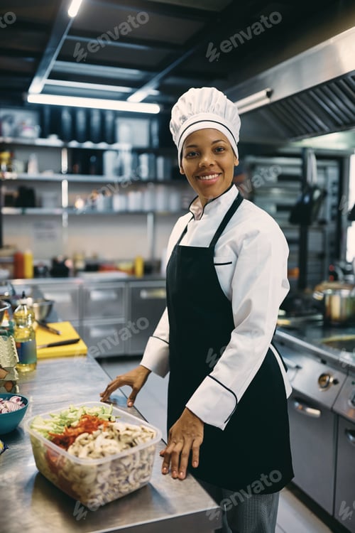 Preview: Happy African American chef preparing food in a restaurant.