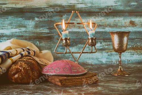Preview: Shabbat eve table with covered challah bread, candles and cup of wine.