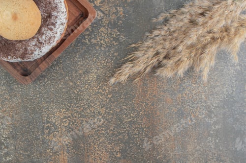 Preview: Feather grass stalks next to a cookie and donut on a small tray on wooden background