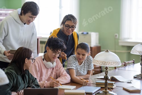 Preview: Two students pointing at notes of teenage guy while choosing name for project