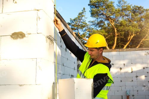 Preview: Construction worker at construction site measures the length of the window opening