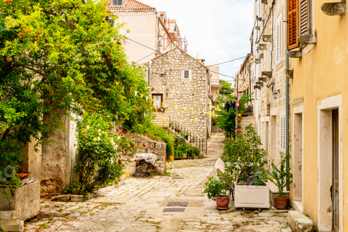 Preview: Cobblestone street in a quaint European village with stone buildings and greenery