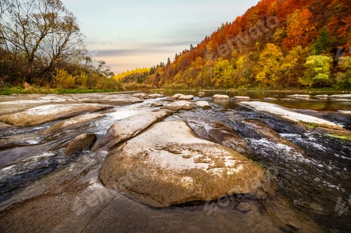 Preview: Stone bank against colorful trees growing on hills in autumn