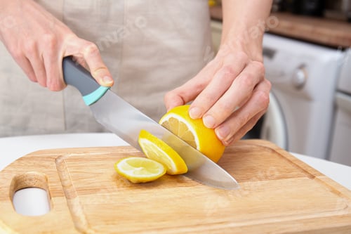 Preview: Hand Slicing Lemon with Knife on Wooden Board
