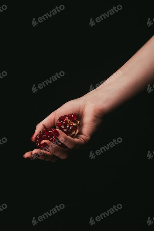 Preview: Cropped image of woman holding pomegranate in hand isolated on black