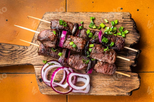 Preview: Shish kebab with beef and lamb meat, onion and herbs on Skewers. Orange background. Top view