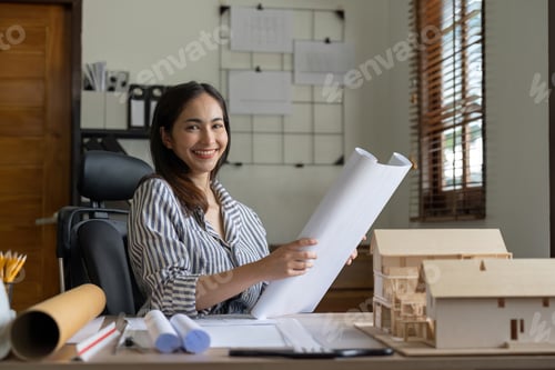 Preview: Female asian architect working on blueprint at office.