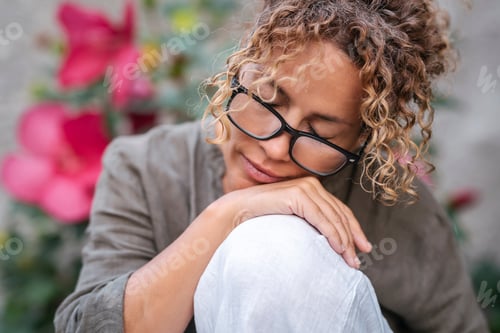 Preview: One woman alone outdoor with peaceful serene espression in the garden sitting and relaxing