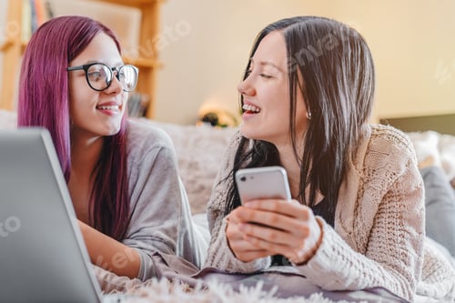 Preview: Two beautiful young women relaxing on the living room floor with laptop computer