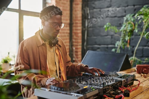 Preview: African American guy with headphones on neck touching vynil disks