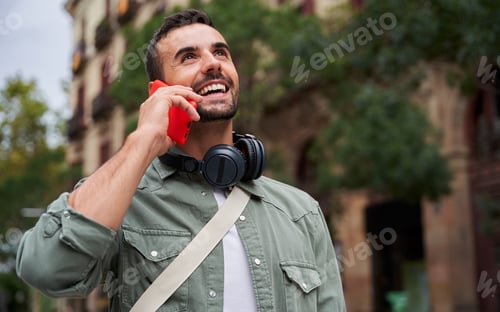 Visualização: Homem alegre andando ao ar livre na cidade falando ao telefone.