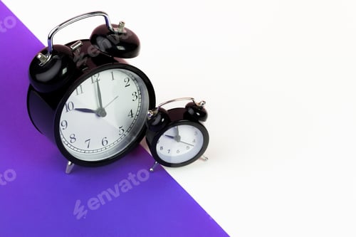 Preview: Vintage black alarm clock on lilac background. Close up