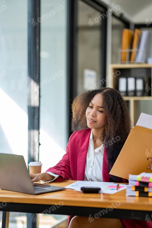 Preview: An African businesswoman holds a brown envelope on a table and opens a sheet of business information