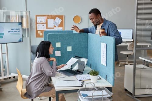 Preview: Two colleagues chatting in office over partition wall